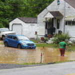 green bag road flooding up to car grill